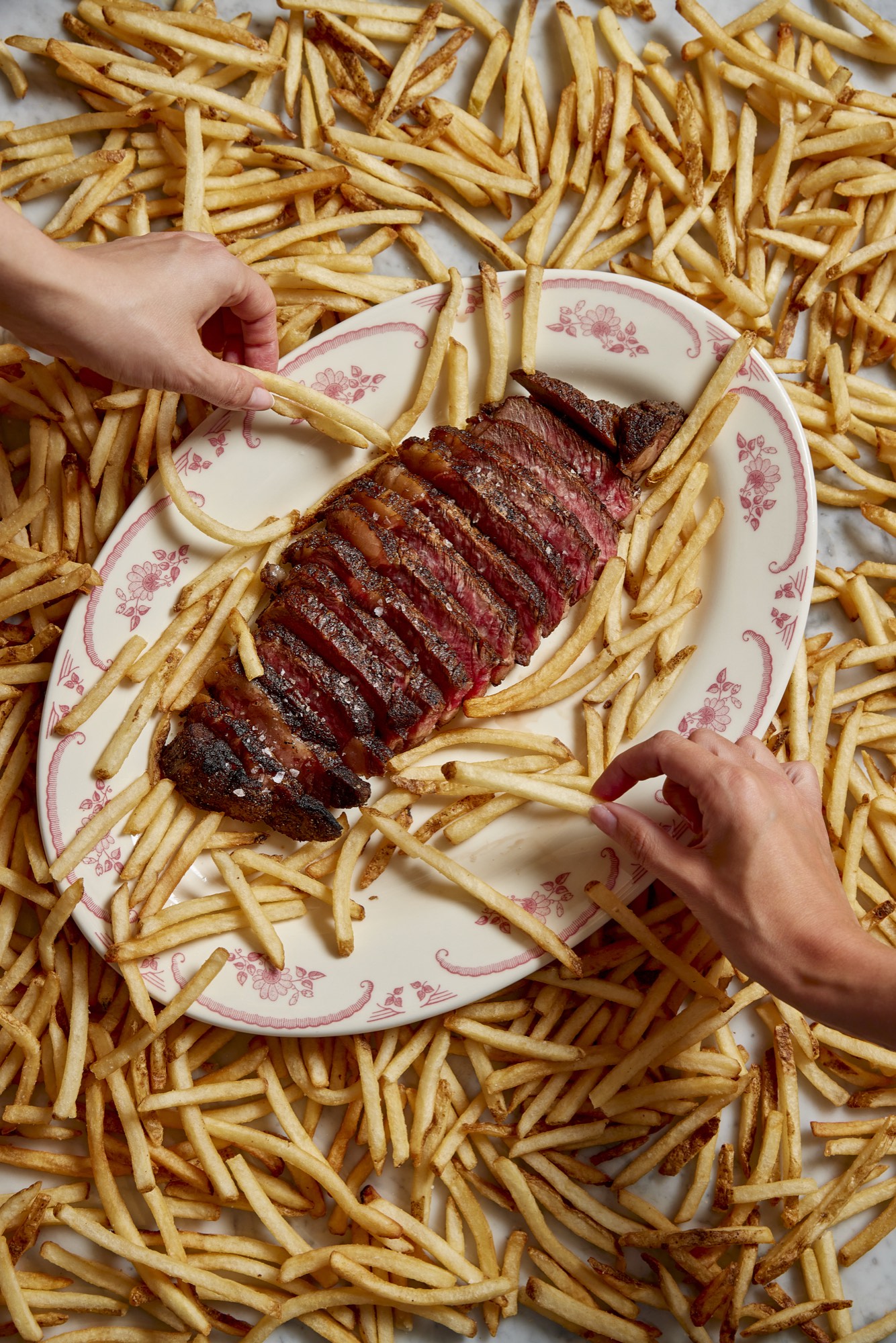 Sliced dry-aged steak with Endless Fries at Sirrah, a modern French steakhouse in the Meatpacking District NYC